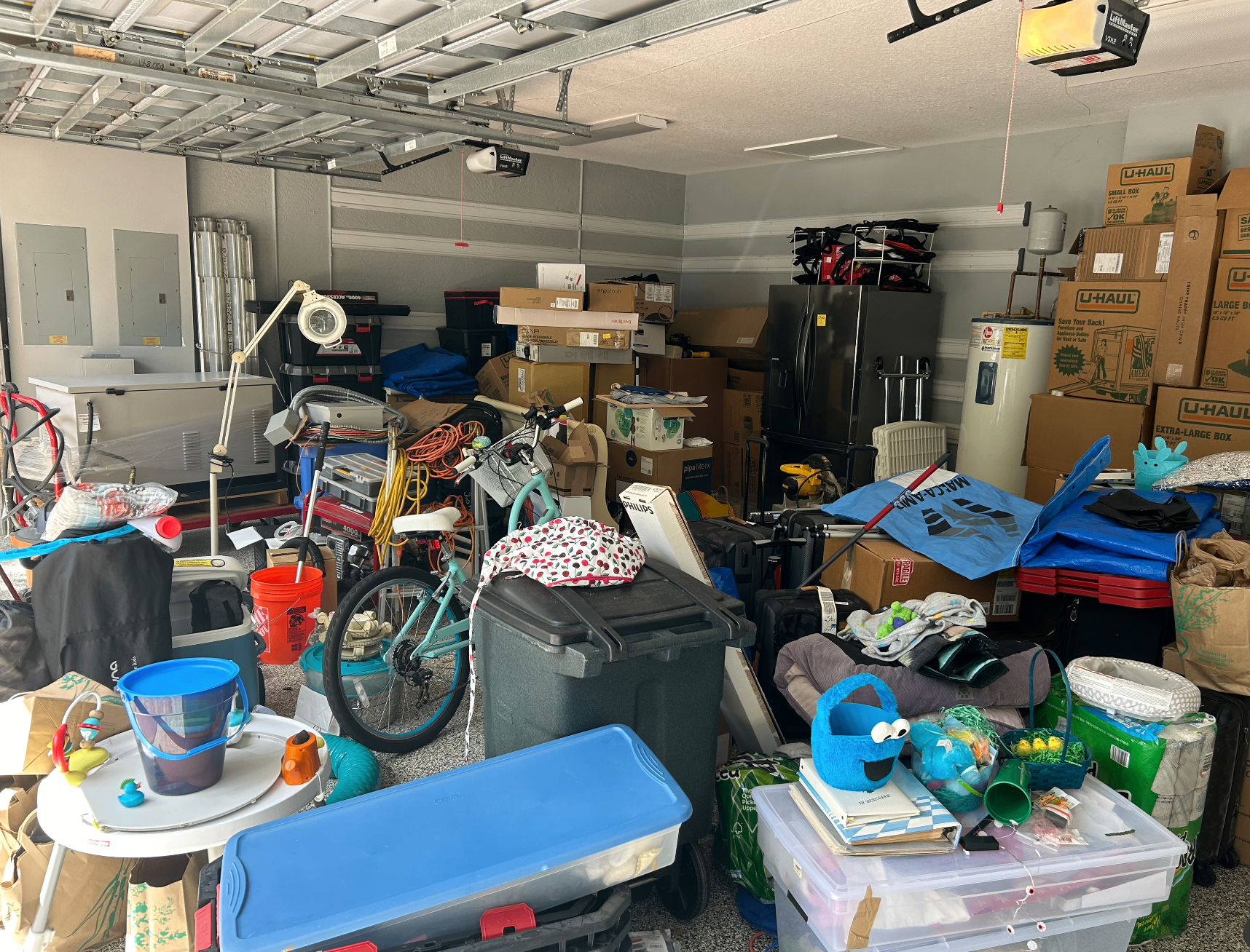 Cluttered South Florida garage filled with boxes, bins, a bicycle, and household items before a Fresh Start Junk Removal cleanout